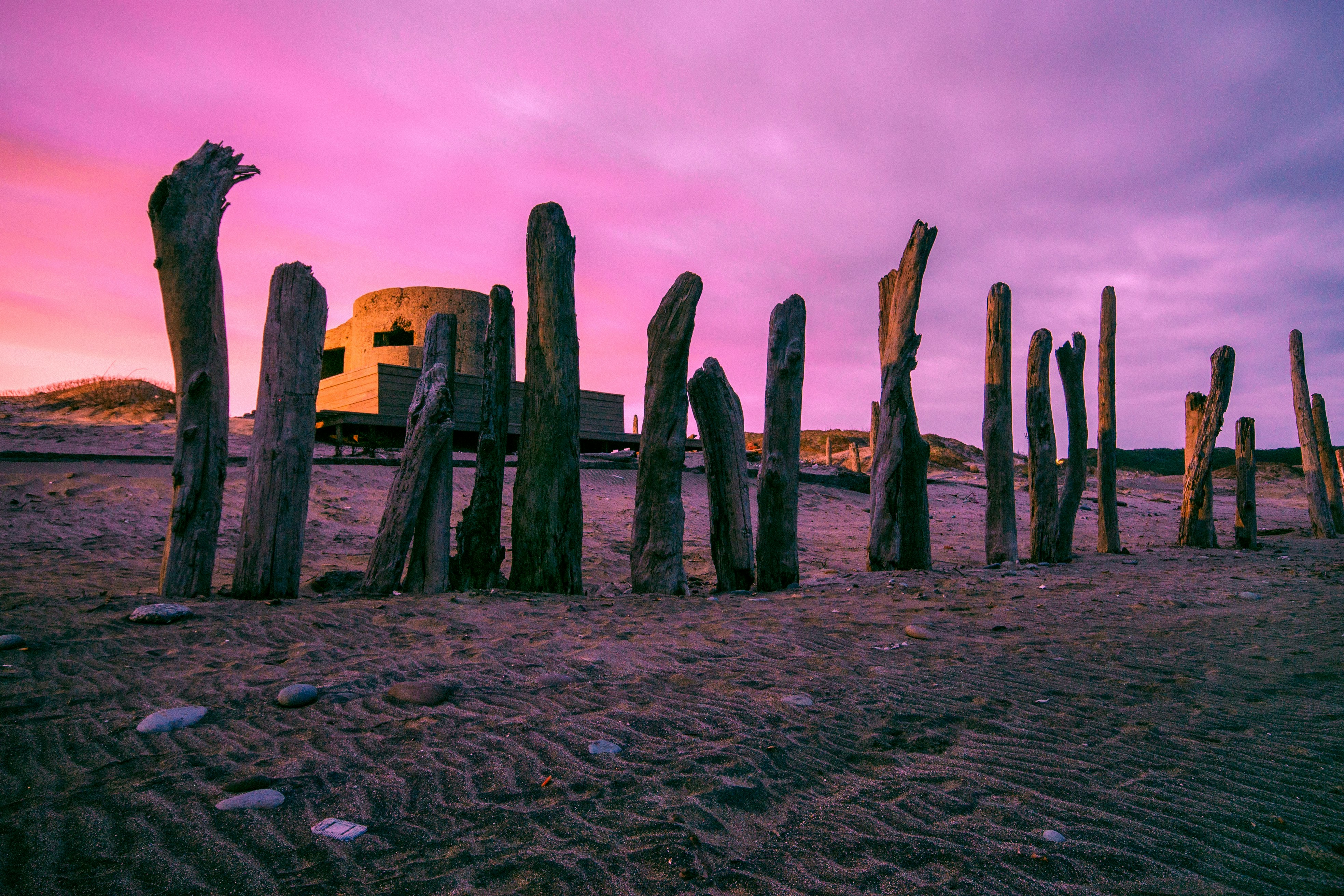 brown wooden posts on brown sand under cloudy sky